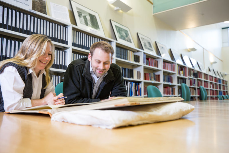 a man and woman look at papers on the table in front of them
