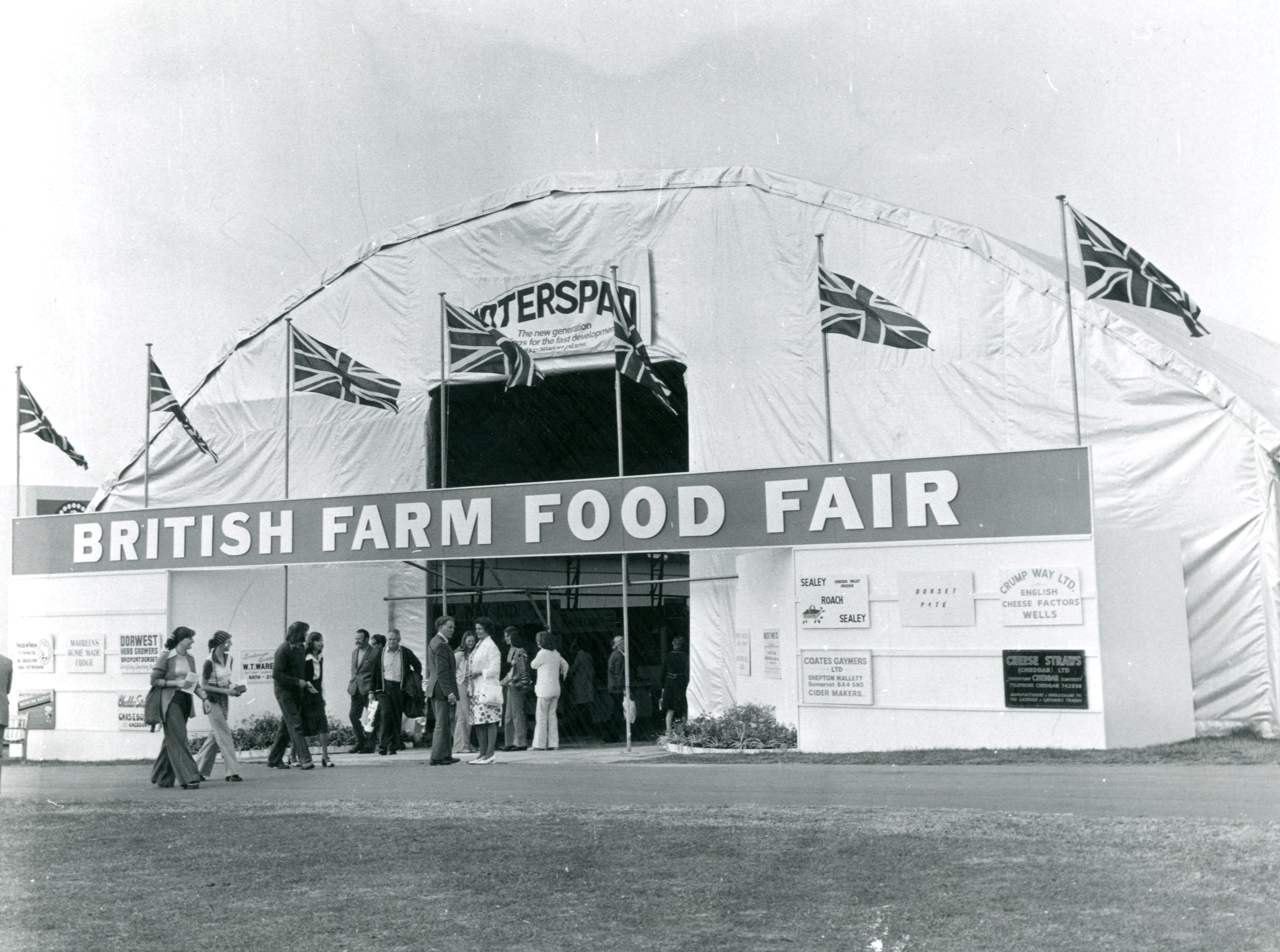Black and white photograph of domed white tent with Union Jack flags out in front. The sign on the tent reads 'British Farm Food Fair'.