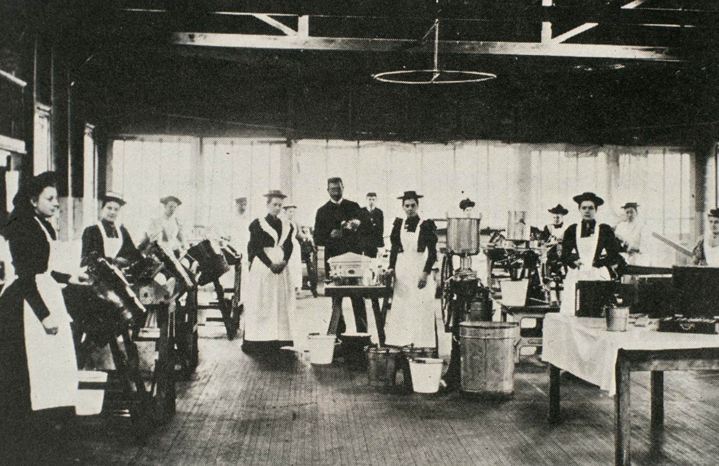 Black and white photograph of over 10 female students of the butter school and 1 man stood facing the camera.
