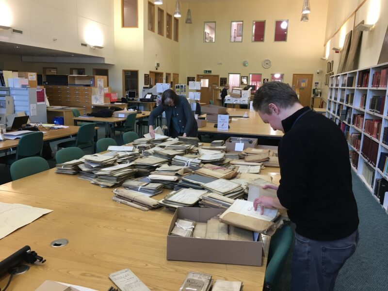 Two people surrounded by boxes and papers