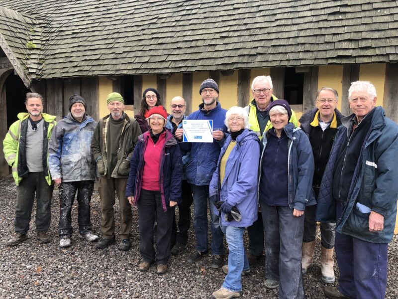 Group of people standing in front of a reconstructed Saxon longhouse