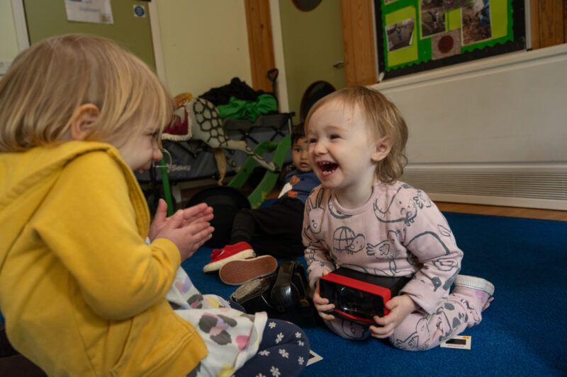 Two children laughing and playing with vintage toys.