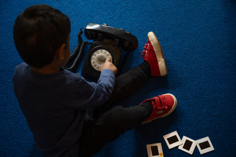 A child playing with a vintage telephone, photographed from above.