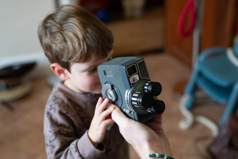 Child looking through a vintage camera.
