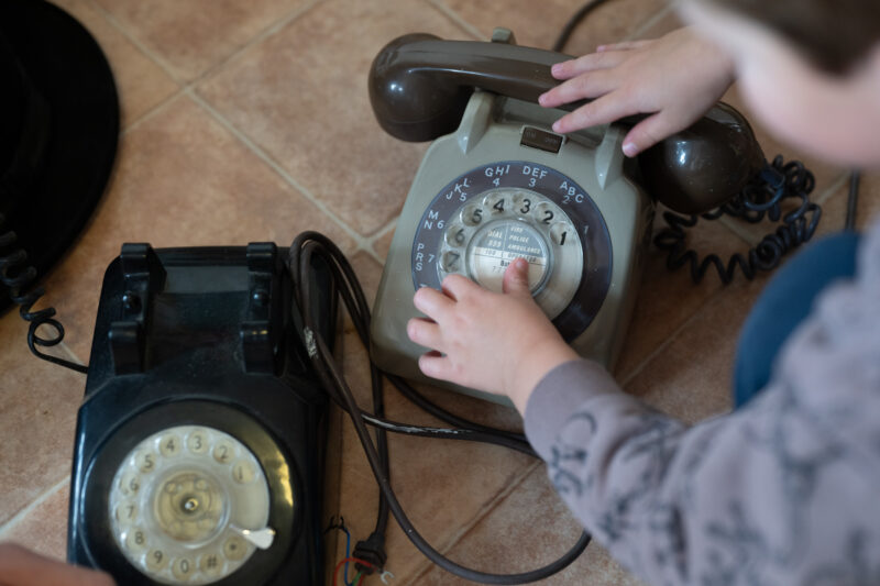 Small children's hand playing with old rotary telephones, photo taken from above.