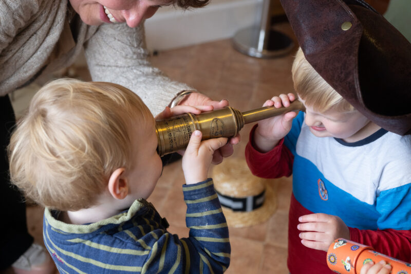 Children looking into either end of a telescope.