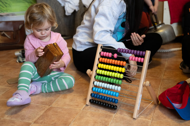 Child playing with a telescope box next to a toy abacus used for counting.