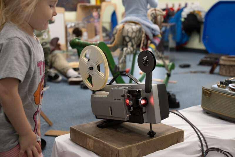 Child looking at a vintage recording camera.