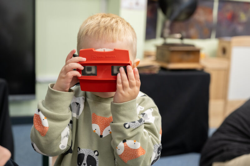 Child looking at the camera through a viewmaster toy.