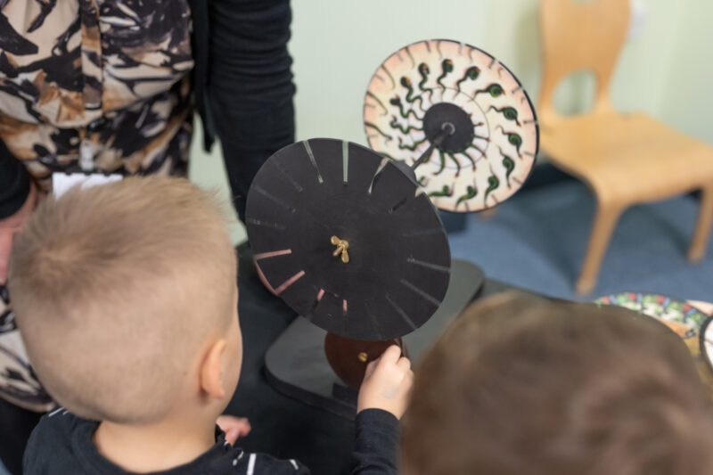 Child looking through and playing with a praxinoscope.