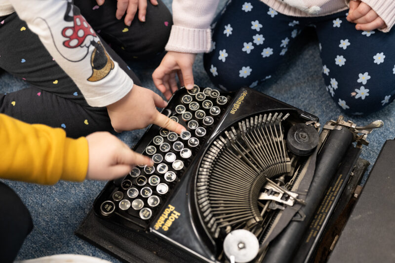 Children's hands touching a vintage typewriter (photo taken from above).