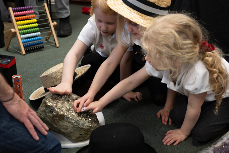 Children touching a large lump of fools gold.