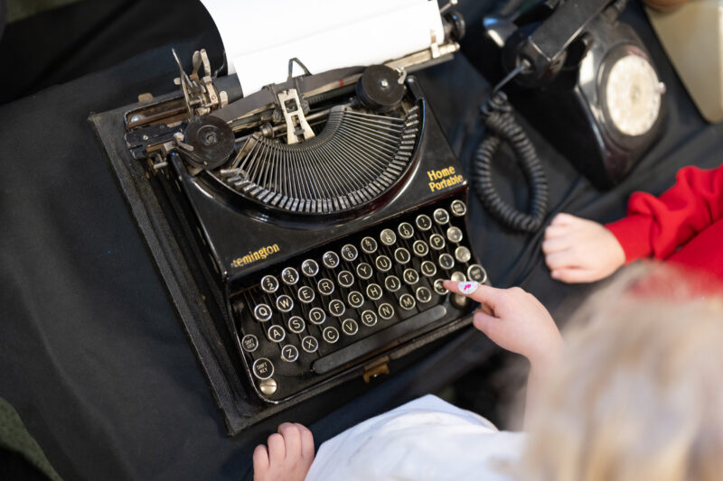 View from above of a child playing with a vintage typewriter.