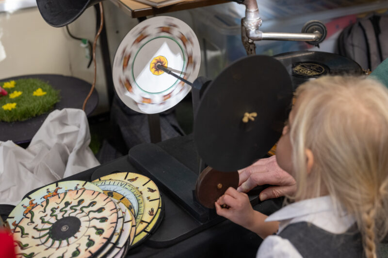 Child looking through a spinning praxinoscope.
