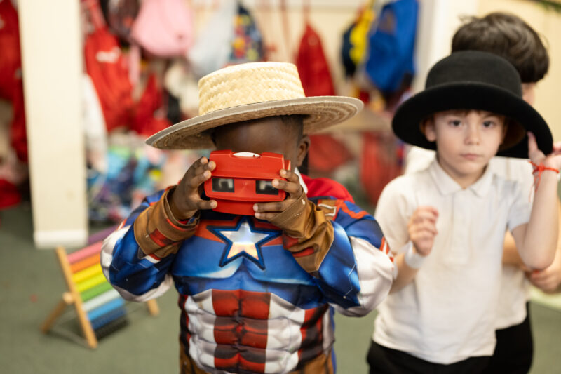 Child dressed in a superhero costume playing with a viewmaster toy.