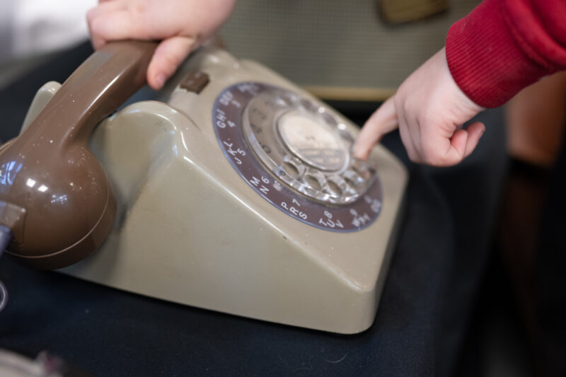 Close up photograph of a child using a vintage rotary telephone.