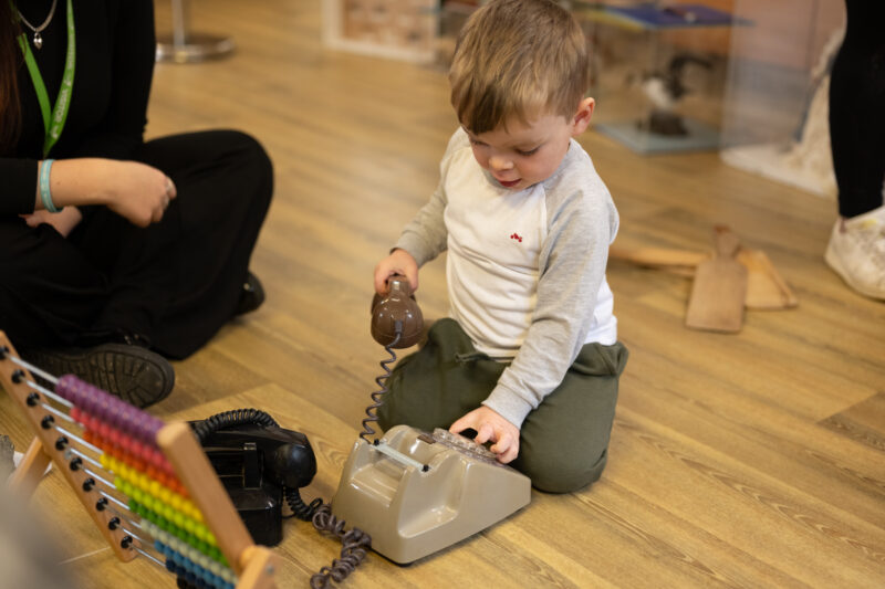Small child playing with a vintage rotary telephone.