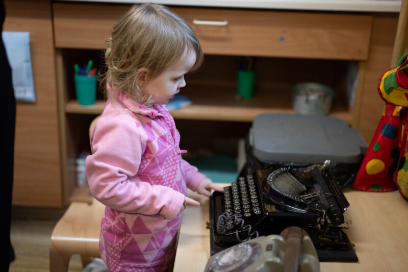 Small child playing with vintage typewriter.