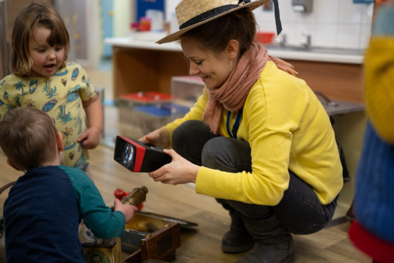 Adult showing small children how to use a vintage toy.