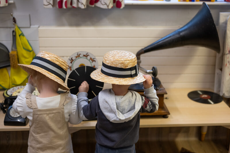 Children facing away from the camera, playing with a gramophone.