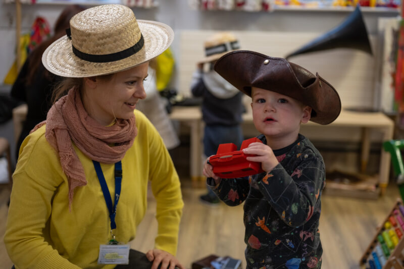 Adult and child wearing hats and playing with the vintage objects.