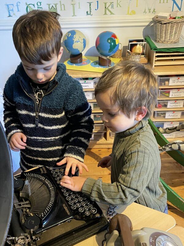 Two children playing with a vintage typewriter.