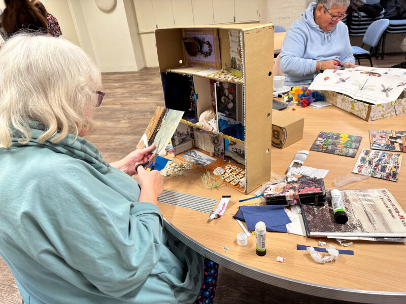 Woman cutting with scissors to create artwork.