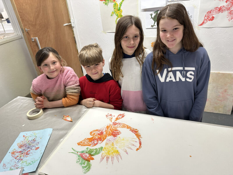 Group of children posing in front of their artwork.