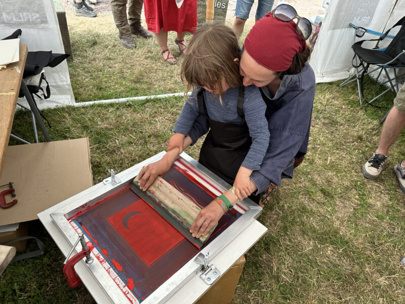 Parent helping their child create a screen print.