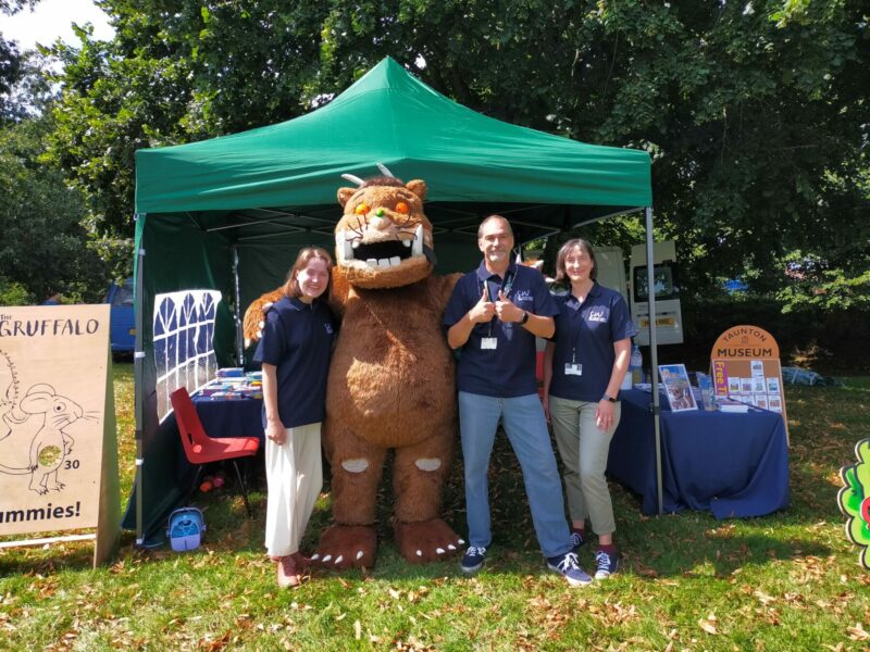 Team of people stood with the Gruffalo in front of a green gazebo.