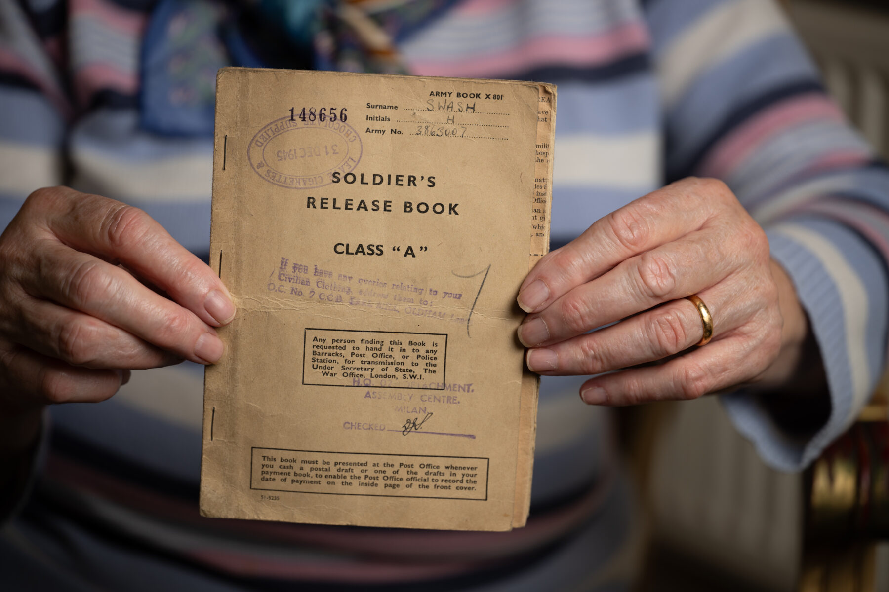 A woman holding a World War 2 soldiers book to the camera with both hands.