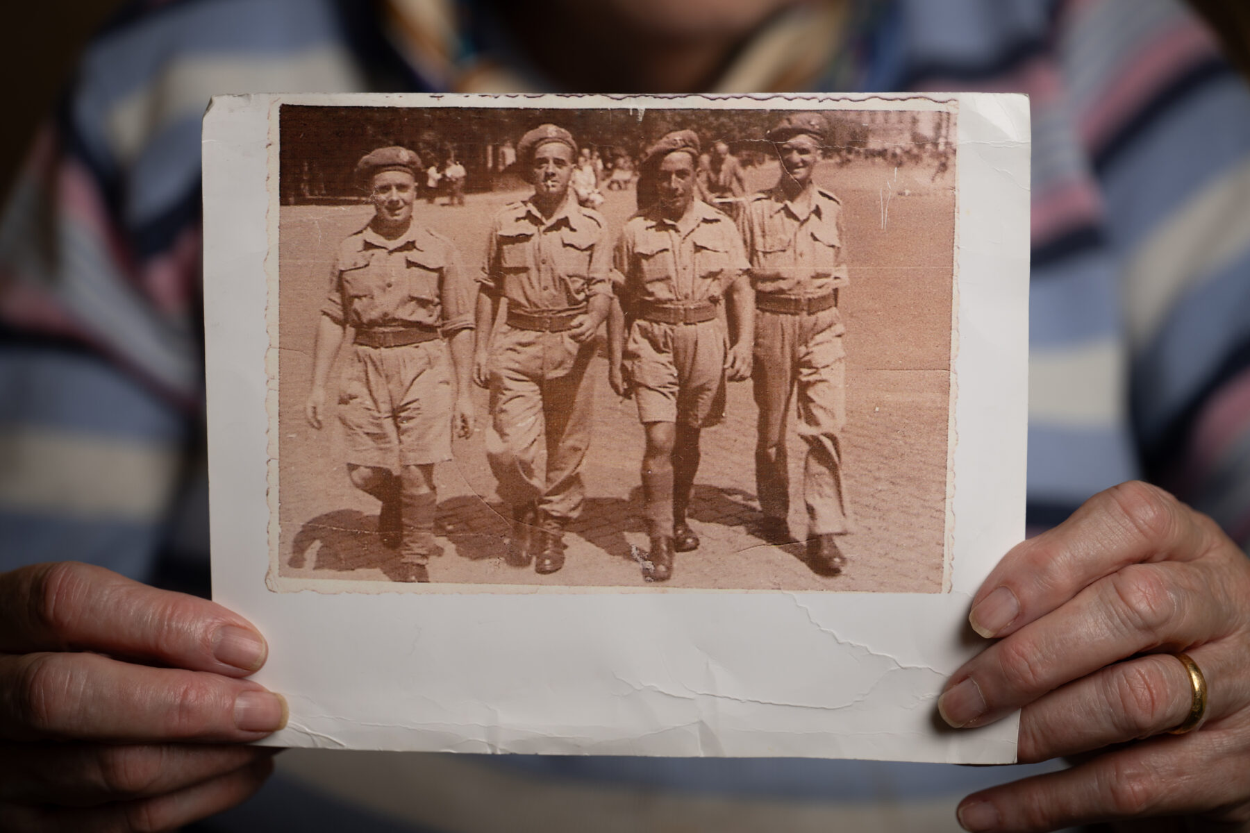 A woman holding an old photograph of some soldiers stood in a line.