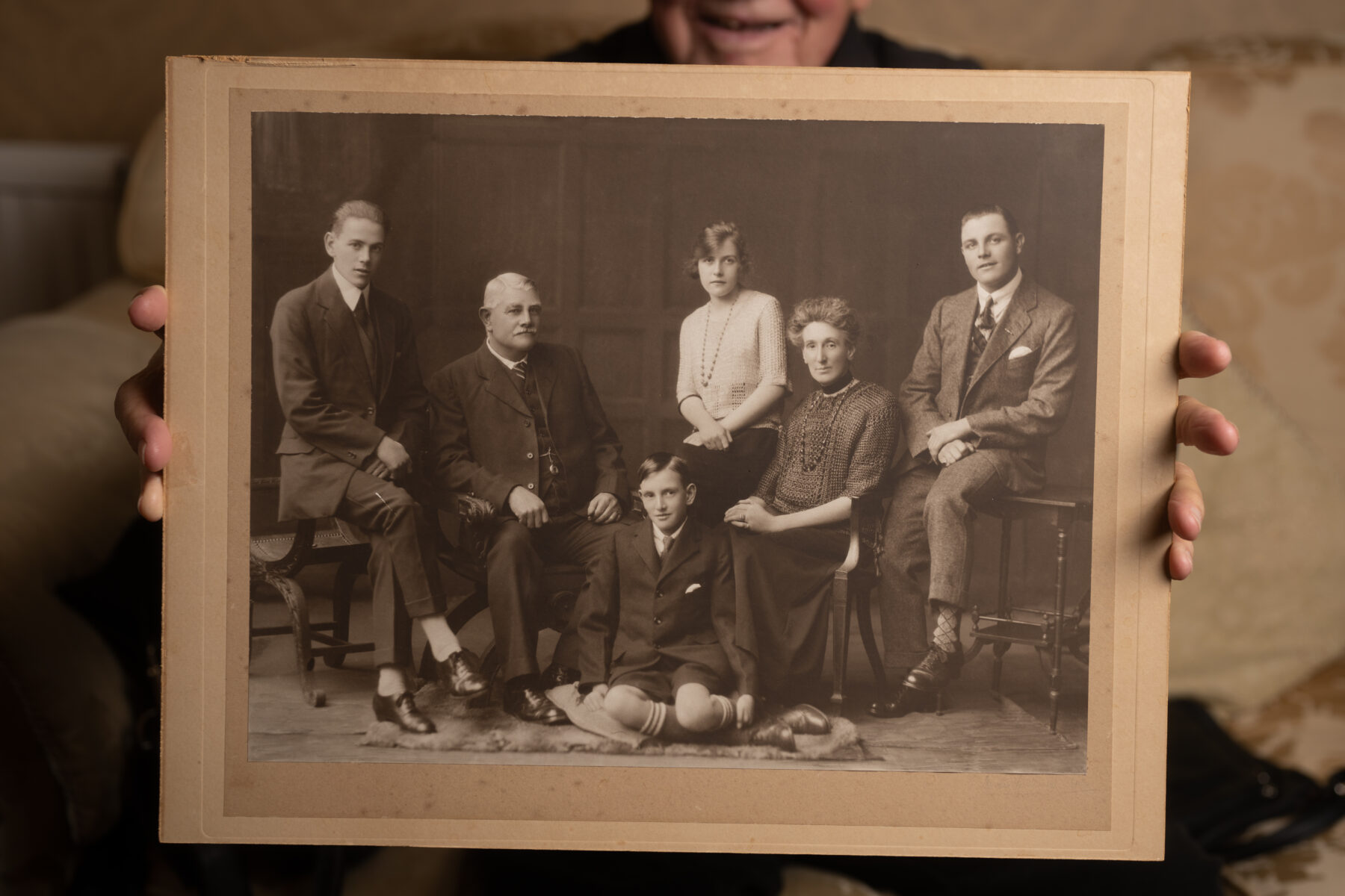 A man holding a large family portrait up to the camera.