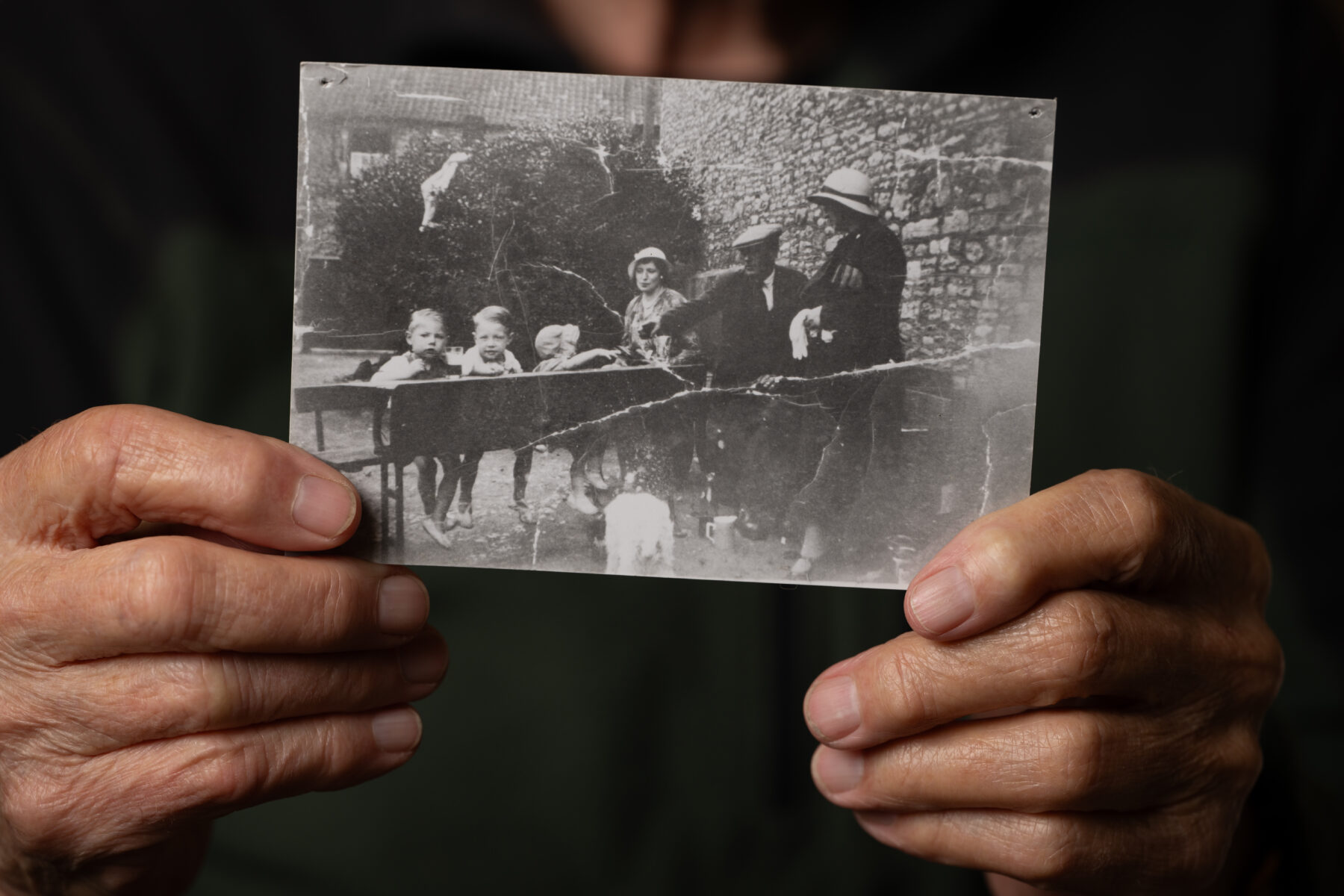 Someone holding an old photograph, showing some children and adults sat around a desk.
