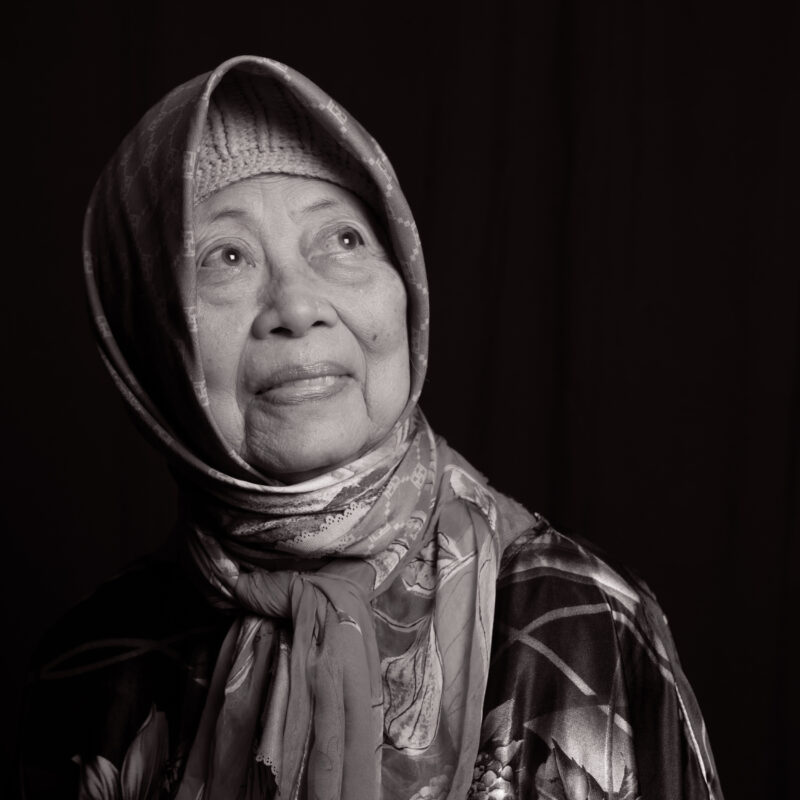 Black and white portrait of an older woman in a head scarf.