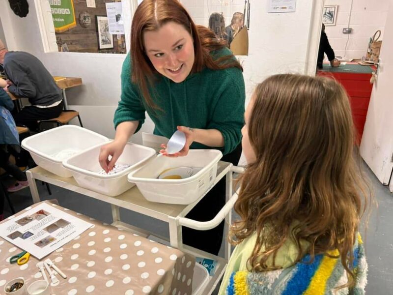 Young woman helping a child with a craft activity.