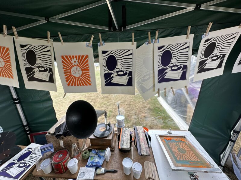 Table full of screen printing equipment and vintage objects under a gazebo.