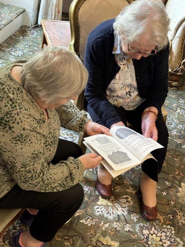 Two elderly women reading a book together.