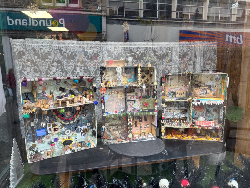 Assemblage artworks displayed in a shopfront window.
