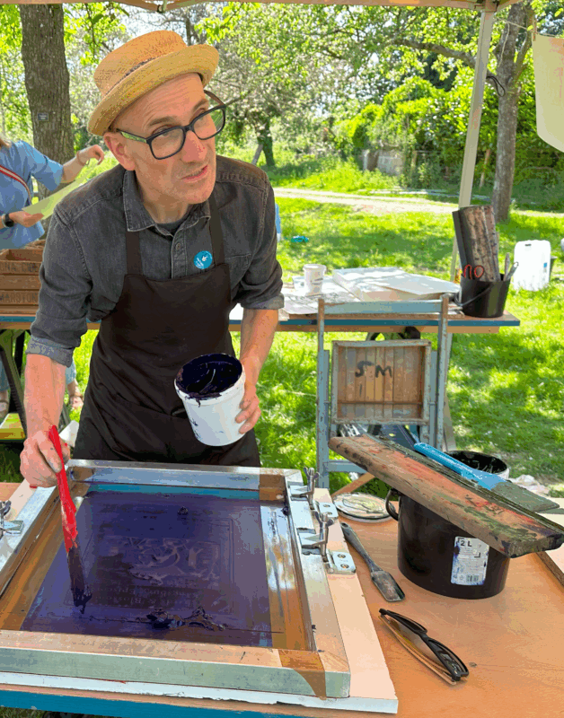 Man wearing a hat applying ink to a screen.