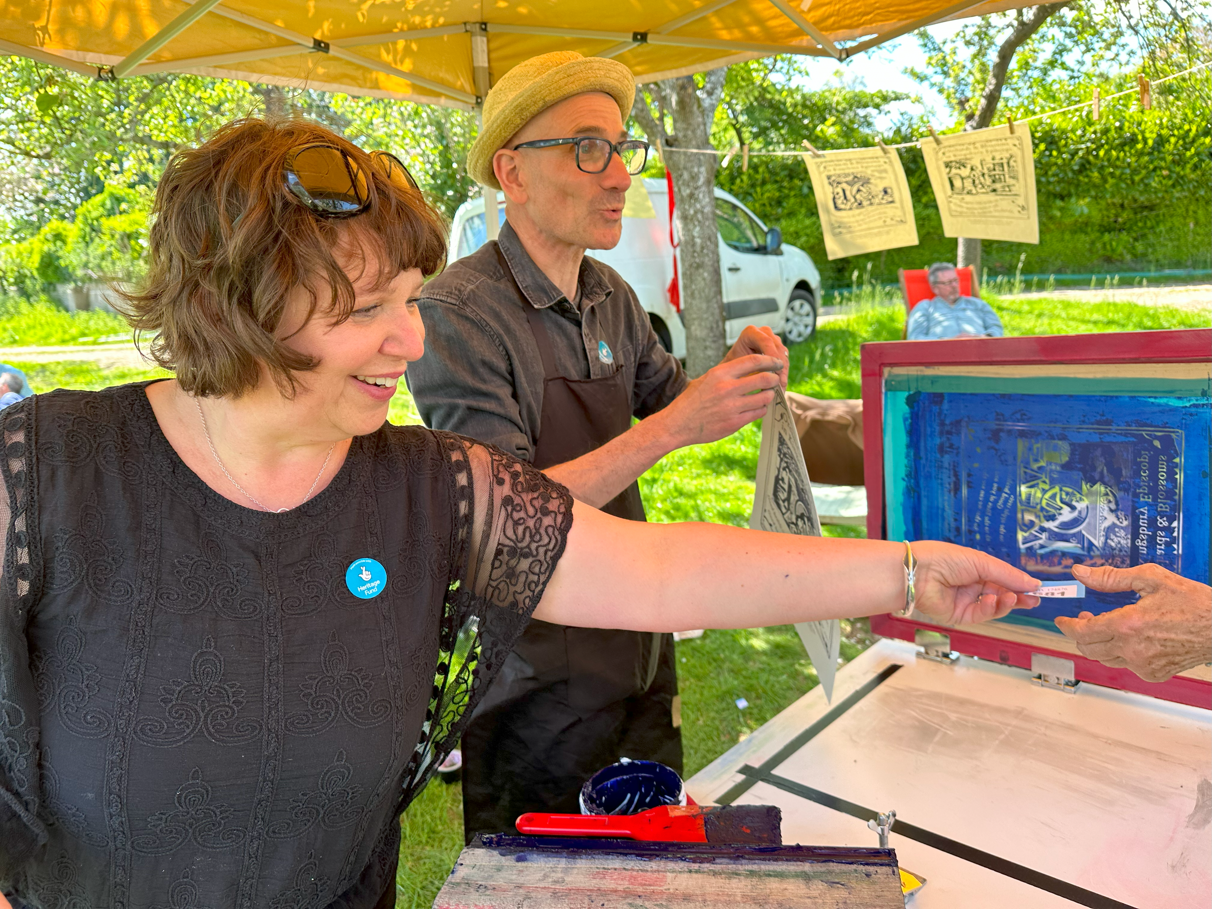 Two people hanging up prints and handing out equipment.