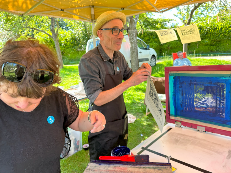 Two people hanging up prints and handing out equipment.