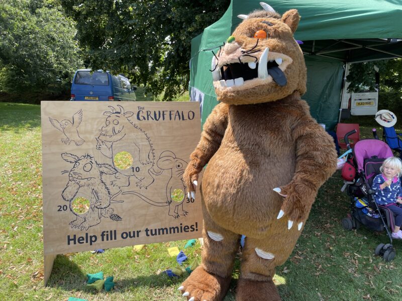 Someone dressed as the Gruffalo stood in front of a marquee.