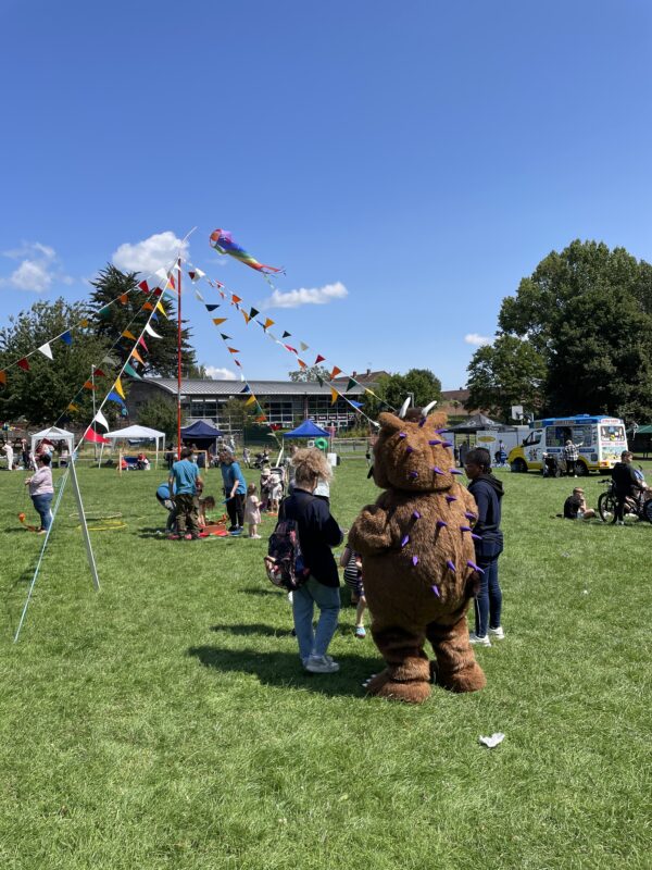 Field with people, decorations and someone dressed as the Gruffalo.