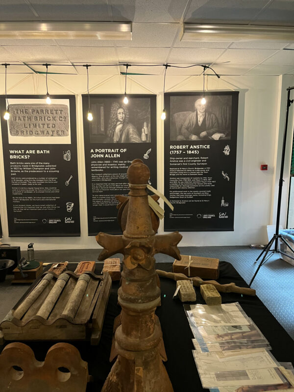 Picture of banners hanging on a wall, with museum display table in front.