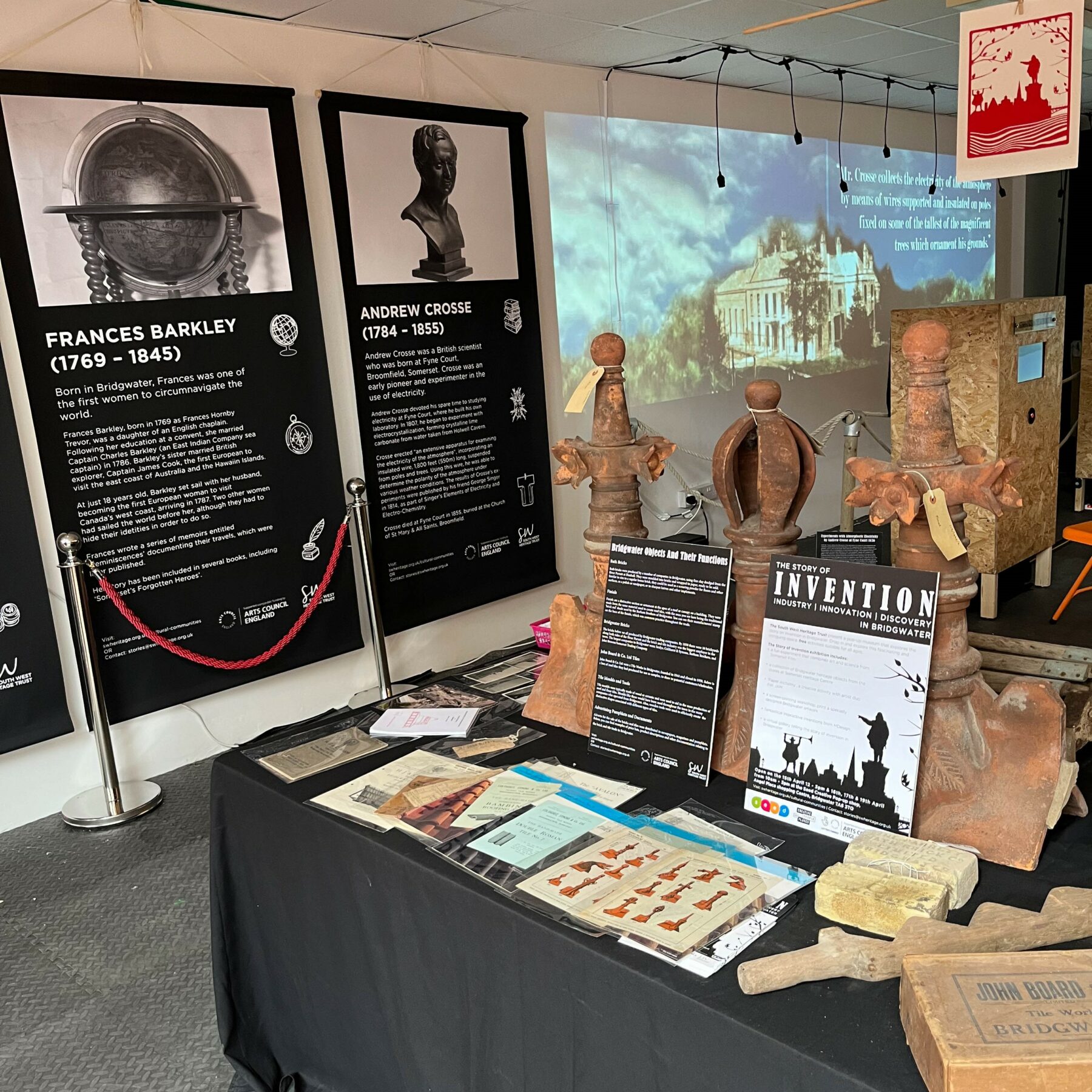 A table full of brick and tile related objects with information banners and projections in the background.