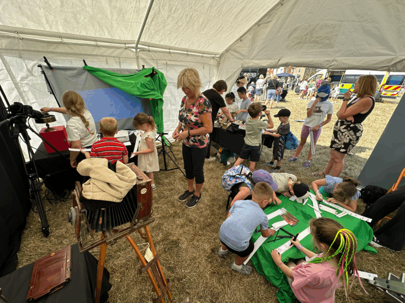 A large group of adults and children taking part in an activity inside the marquee.