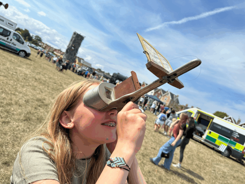A child looking through a Victorian image viewer with a field in the background.