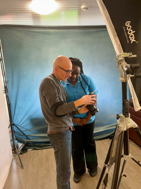 Man showing a woman photos on a digital camera, with the photography background and equipment around them.