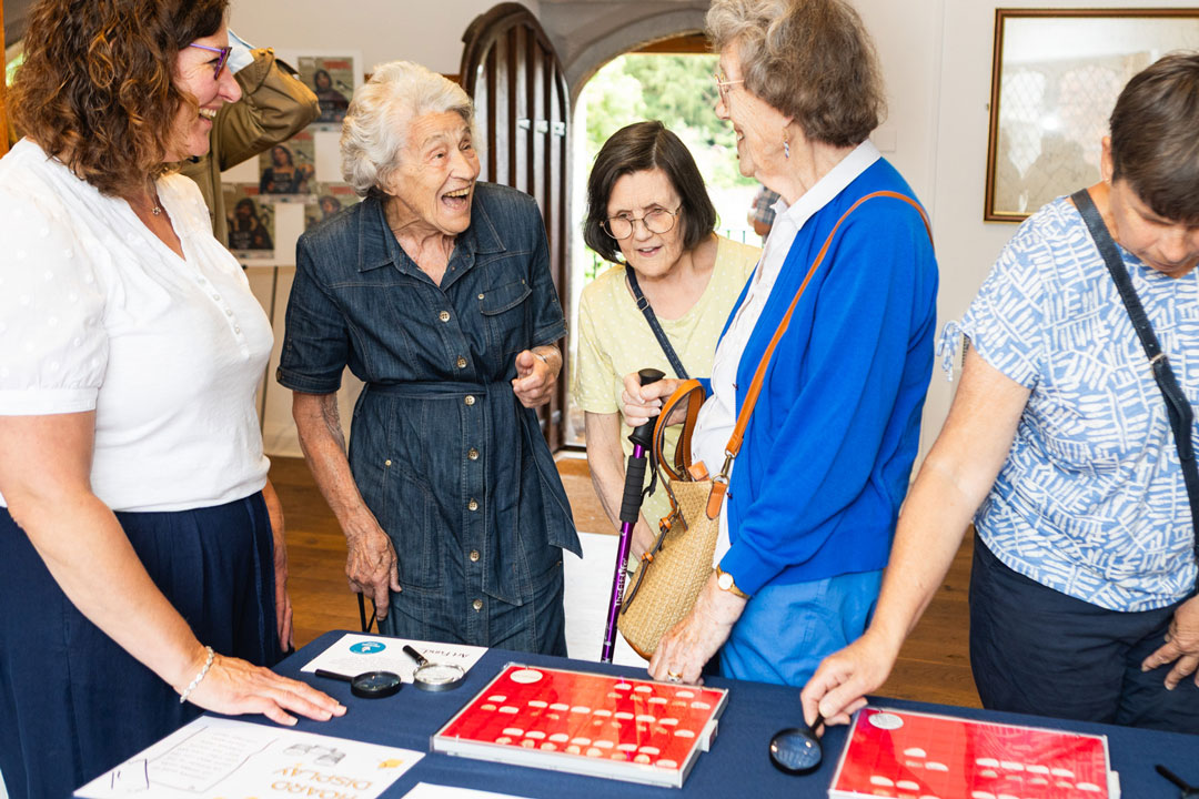 A group of women standing around a display of coins laughing.